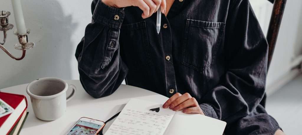 person writing notes in book