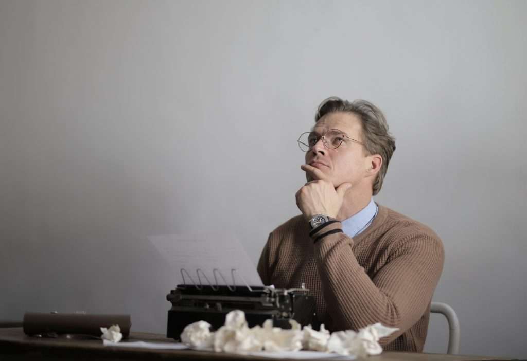 man sitting at typewriter thinking