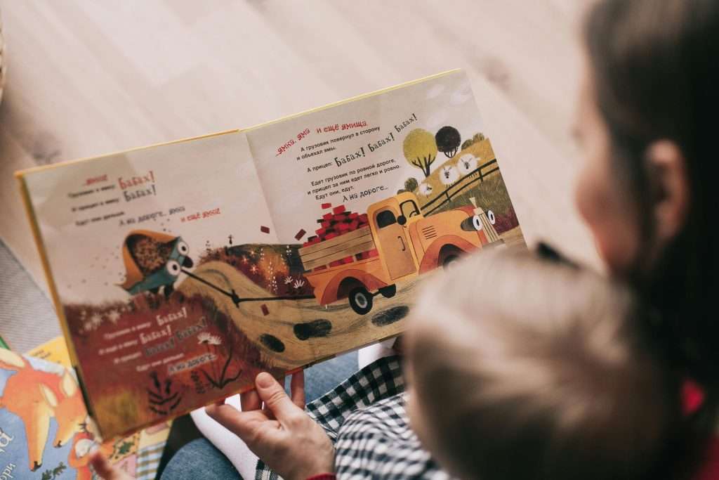 child and adult reading picture book together