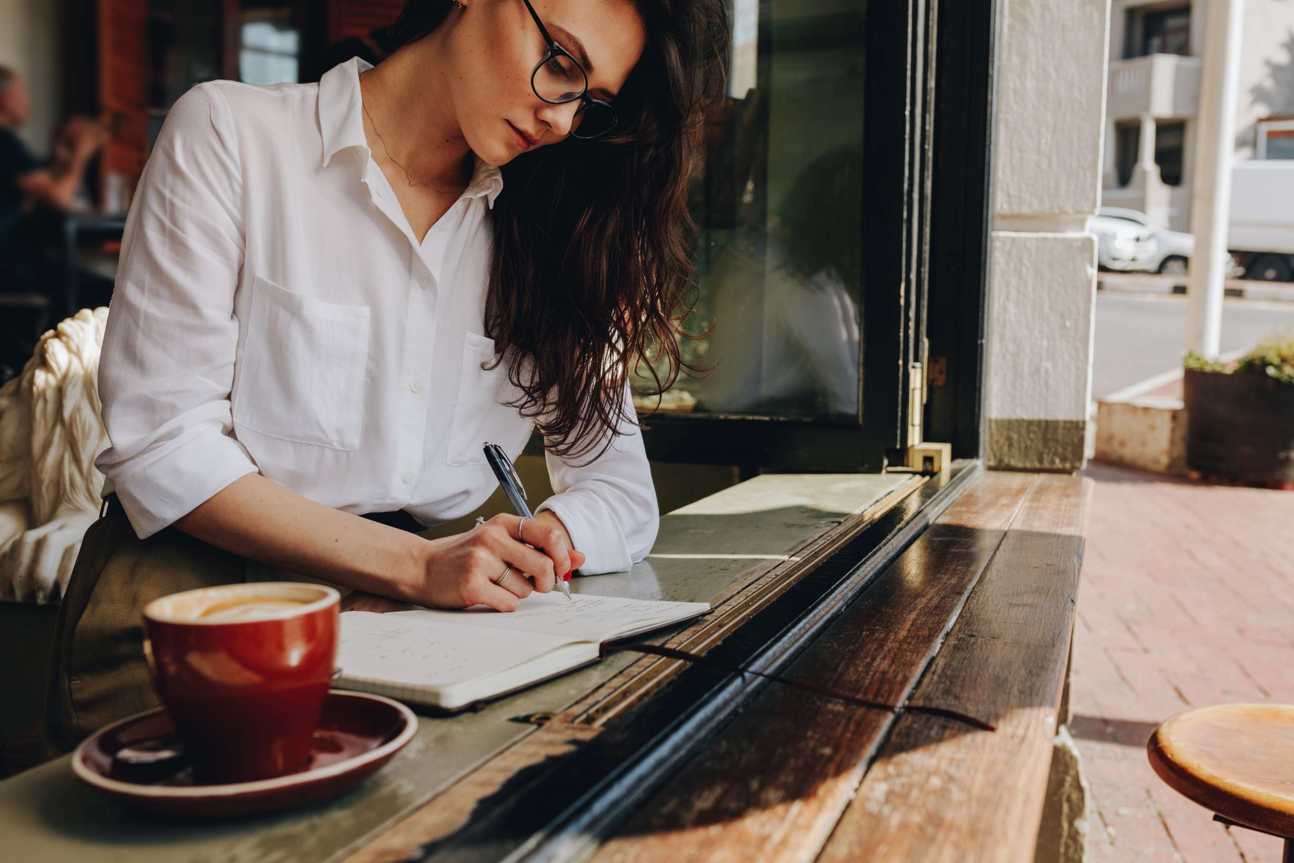 a woman taking notes for her book while sitting in the cafe